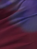 Vestido corto de satén con escote profundo tipo halter y espalda descubierta. Presenta un diseño estampado con degradado en tonos bordó y violeta.