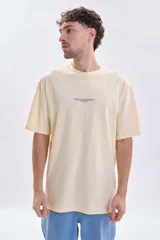 Remera de corte oversize color amarillo claro, con cuello redondo y estampa minimalista en el centro del pecho.