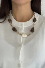 Collar de cadena de eslabones dorados con cuentas de resina en tonos marrón y crema. Cuenta con cierre de mosquetón ajustable.