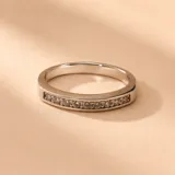 Anillo de oro blanco 18K con diseño medio sin fin, decorado con una línea de circonias engastadas en el frente.