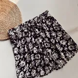 Short negro con estampado floral blanco, con cintura elastizada y lazo para ajustar.