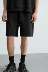 Bermuda de algodón color beige claro, corte relajado (relaxed fit), con cintura elástica ajustable mediante cordón y bolsillos laterales y trasero de plastrón.