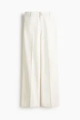 Pantalón de jean color crudo, de corte wide leg y tiro alto. Presenta cierre frontal con doble botón metálico y pliegues marcados en la parte delantera.