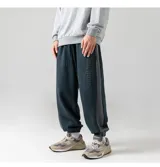 Pantalón de estilo babucha/jogging, color azul oscuro, confeccionado en tela tipo gamuza suave. Presenta una guarda lateral blanca y cintura elástica con cordón regulable. Cuenta con tres bolsillos: dos delanteros y uno trasero.