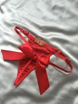 Tanga roja de tiras regulables con dije de strass con letras y gran lazo de raso al frente.