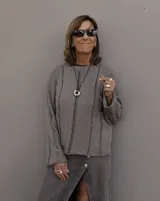 Collar con dije de forma irregular en tonos dorados y plateados, suspendido de un cordón doble de algodón negro.