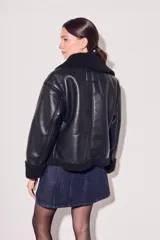 Campera negra de cuero sintético con cuello y puños de piel sintética. Corte oversize y cierre frontal con cremallera.