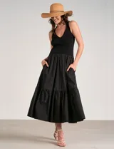 Vestido maxi combinado negro de la marca Elan, con torso de punto acanalado con escote en V pronunciado y breteles anchos. Cuenta con corte a la cintura y falda larga fluida con volumen, bolsillos laterales y volante fruncido en el ruedo.
