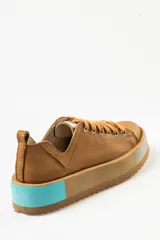 Zapatillas deportivas color marrón con cordones, suela gruesa con detalles en celeste y gris.