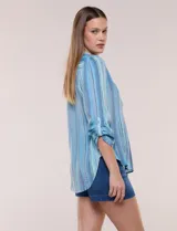 Blusa de gasa de la marca Zac & Rachel, con estampado de rayas verticales en tonos azules, celestes y lilas. Presenta cuello a la base con escote en V, abertura central con botones, detalle plisado en el frente y mangas de largo regulable con presilla y botón.