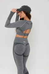 Conjunto deportivo de dos piezas compuesto por un top de manga larga con abertura en la espalda y calzas de tiro alto con diseño de contorno moldeador. Ambas prendas presentan un acabado jaspeado y detalles de tejido técnico con textura.