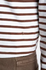 Remera de manga larga ajustada al cuerpo, con cuello redondo. Presenta un patrón de rayas horizontales anchas en color blanco y marrón oscuro.