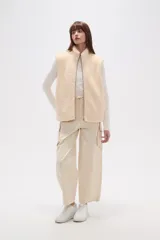 Chaleco sin mangas de textura peluche (teddy) color crema, con cuello alto y cierre frontal de cremallera.