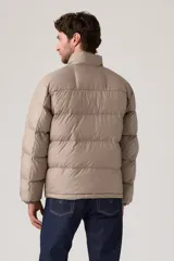 Campera puffer de corte corto y diseño acolchado horizontal, color beige. Cuenta con cierre frontal completo y logo de la marca en el pecho.