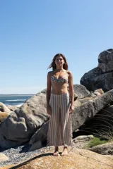 Pantalon de tiro bajo con corte recto y ancho, confeccionado en tejido de lino y algodón con estampado de rayas verticales multicolores. Presenta aberturas laterales en los bajos con tiras para anudar y cierre lateral.