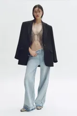 Jean de pierna recta en denim de algodón rígido, con diseño de aberturas laterales en la cintura decoradas con cristales brillantes. Presenta un corte holgado, cintura con borde desflecado y bajo deshilachado.