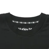 Remera Hurley de corte boxy, con cuerpo en color negro y mangas en color verde militar. Presenta un bolsillo frontal en el pecho en tono verde con etiqueta de la marca y cuello redondo.