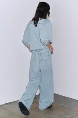 Camisa de denim celeste con cuello solapa, manga corta abullonada y cierre frontal con botones.