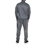 Conjunto deportivo Umbro compuesto por campera con cierre frontal y pantalón de jogging, ambos en color negro con detalles de bandas laterales y cierres en blanco. La campera presenta cuello alto y bolsillos laterales, mientras que el pantalón cuenta con ajuste elástico en la cintura y tobillos.