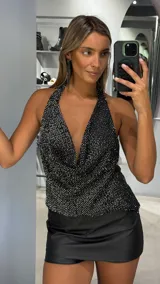 Top halter negro con acabado brillante y efecto drapeado en el escote. Presenta un diseño sin mangas con espalda descubierta y ajuste en el cuello.