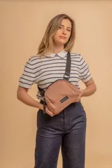 Bandolera pequeña de diseño moderno, confeccionada en tafeta liviana y resistente. Cuenta con cierre superior, correa ancha ajustable y logo frontal de la marca.