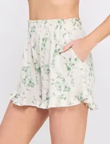 Short de lino y viscosa color beige con estampado botánico en tonos verde agua, tiro alto con cintura elastizada, corte holgado y ruedo con volado fruncido.