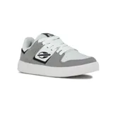 Zapatilla urbana Mormaii modelo Joaca, color gris claro y blanco, de caña baja y estilo skate. Presenta cordones blancos y un logo lateral con un diseño abstracto en negro.