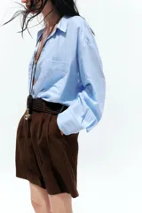 Bermuda de tiro alto color azul marino, con pinzas delanteras, bolsillos laterales y cinturón trenzado color marrón.