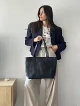 Cartera tipo shopper de cuero marrón texturado, con doble asa de hombro y un bolsillo frontal amplio con cierre de imán.