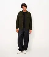 Camisa de manga larga confeccionada en sarga de algodón color verde militar. Presenta cuello inglés, cierre frontal con botones y dos bolsillos con solapa en el pecho.