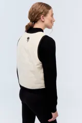 Chaleco negro de pana con bordes color beige y lazos de ajuste frontales.