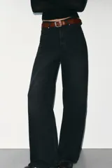 Jeans de mezclilla en color negro gastado, tiro alto, diseño de cinco bolsillos y corte de pierna ancha extra larga. Cuenta con cierre frontal de cremallera y botón metálico.