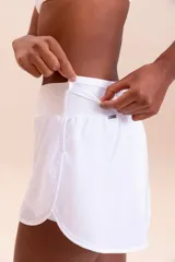 Pollera deportiva color rosa fucsia, con estampado en relieve de texto. Es de corte corto con ruedo redondeado y cuenta con shorts internos.