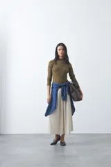 Polera de tejido de punto color celeste, con cuello alto y textura de pequeños puntos en relieve formando una cuadrícula en el frente y las mangas. De corte ajustado y manga larga.