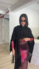 Ruana de tejido de punto color crema con diseño de líneas horizontales caladas y terminación con flecos en el ruedo.