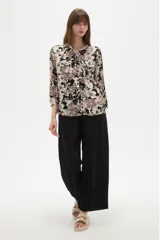 Camisa holgada de viscosa con cuello mao, mangas largas y estampado floral en tonos beige, marrón y negro, con dos bolsillos frontales con solapa.