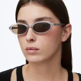 Lentes de sol con montura ovalada de bio-acetato en color rosado traslúcido y lentes marrones polarizadas.