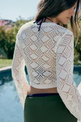 Jersey de punto pointelle color blanco, con cuello redondo y mangas largas y acampanadas.