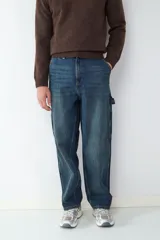 Jean de corte relaxed estilo carpintero, en tono azul oscuro con efecto lavado. Presenta diseño de cinco bolsillos, incluyendo bolsillos laterales utilitarios, cierre de botón y cremallera, y costuras reforzadas.
