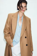 Abrigo largo negro ZARA Woman Collection de corte recto, confeccionado con hilatura de lana. Presenta cuello con solapa de muesca, cierre cruzado de doble botonadura frontal y bolsillos ribeteados en los laterales.