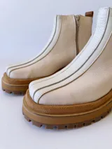 Botas Chelsea de cuero color crudo con elástico lateral, suela track color caramelo y tirador trasero de cuero con textura croco color marrón.