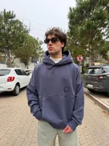 Buzo canguro oversize de algodón, color azul oscuro, con capucha y diseño gráfico circular estampado en la espalda con la inscripción VCP CONCEPTS STUDIO.