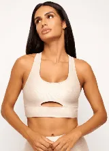 Top deportivo color beige, con textura acanalada y corte con abertura en el centro del pecho.