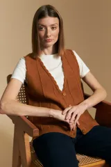 Chaleco tejido color azul, con escote en V, cierre frontal con botones y diseño de líneas verticales en relieve. Presenta terminaciones acanaladas en el ruedo y un borde ondulado en el escote.