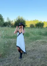 Vestido corto tipo lencero de seda color blanco, con detalles de encaje negro en el escote en V y en el ruedo asimétrico. Presenta breteles finos ajustables y una caída fluida.