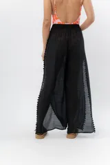 Pantalón ancho de gasa liviana color blanco, con cintura elástica y aberturas laterales decoradas con pompones.