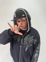 Campera reversible con cierre frontal, diseño oversize. Un lado es de algodón negro con estampados y bordados gráficos, mientras que el otro lado es de tela polar gris de pelo largo. Cuenta con capucha, puños y ruedo acanalados.