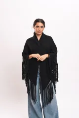 Triángulo tejido artesanalmente en telar manual con hilado mecha de lana merino, de color negro, con diseño envolvente y flecos largos en los bordes.
