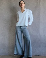 Pantalón de jean estilo wide leg con lavado ácido, tiro medio y ruedo deshilachado.
