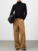 Sweater de punto cardado con textura suave y esponjosa, cuello chimenea y manga larga. Presenta un diseño minimalista y elegante con etiqueta logotipada en la espalda.